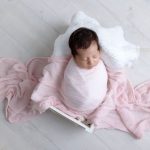 Mädchen bei ihrem Neugeborenenshooting in rosa Tuch eingewickelt