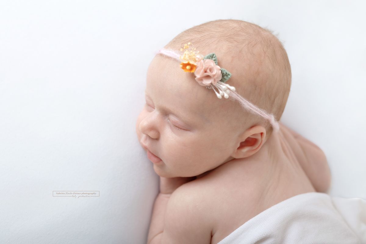 Mädchen in weiß mit dezentem Haarband bei ihrem Baby Fotoshooting