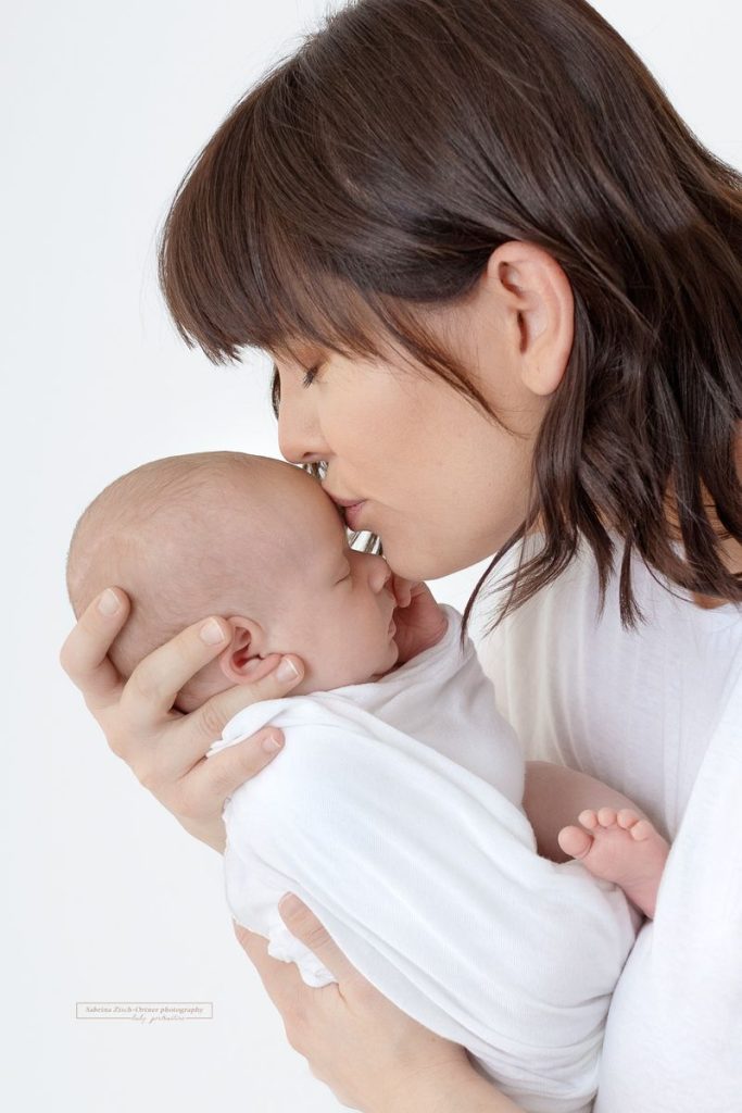 Mama küsst ihre kleine Tochter beim Fotoshooting
