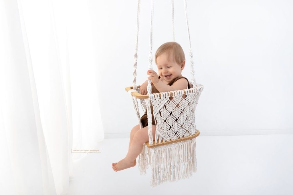 Markame Schaukel beim Babyfotoshooting zum Meilenstein Sitzen