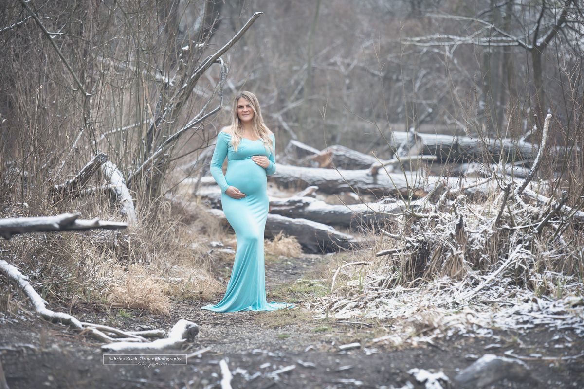 Outdoor Dezember Fotos einer Schwangeren im langen Babybauchkleid