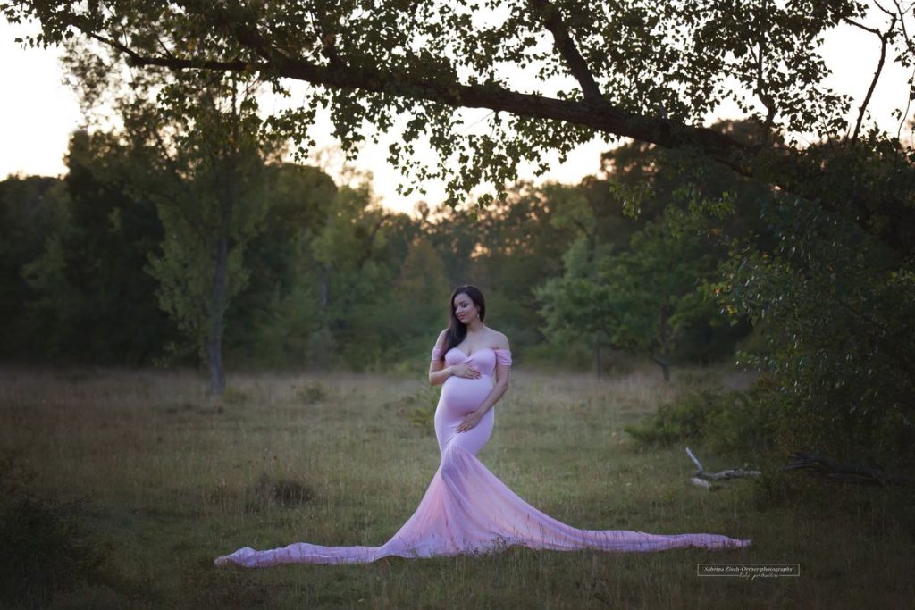 Schwangerschaftsfoto nach Sonnenuntergang in rosa Babybauchkleid