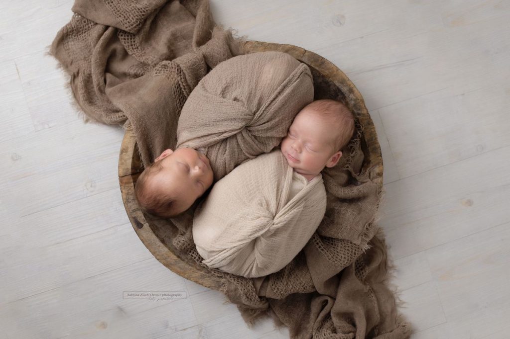 Zwillinge in braun gewickelt in braune Schale schlafend bei ihrem Baby Fotoshooting