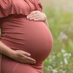 Zwillingsbabybauch in Kupferfarbenen Schwangerschaftskleid beim Fotoshooting