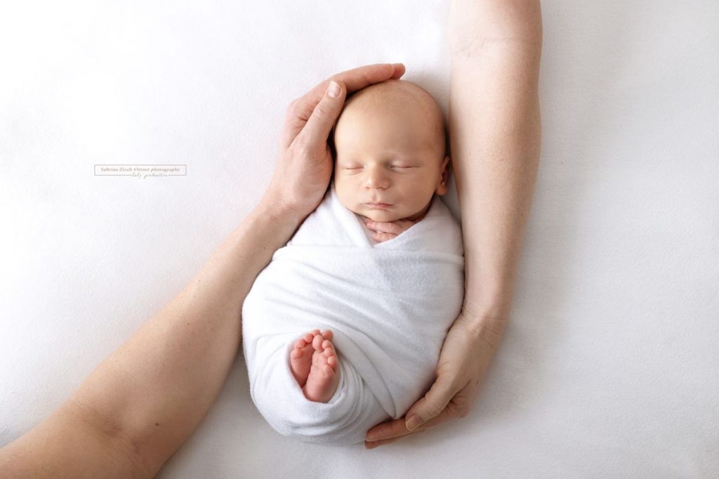 frischgeschlüpfte Baby in den Händen von Mama und Papa