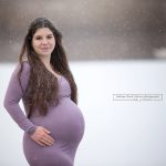 glücklich lächelnde Schwangere in handgeschneiderten Babybauchkleid bei ihren Winter Outdoor Fotos
