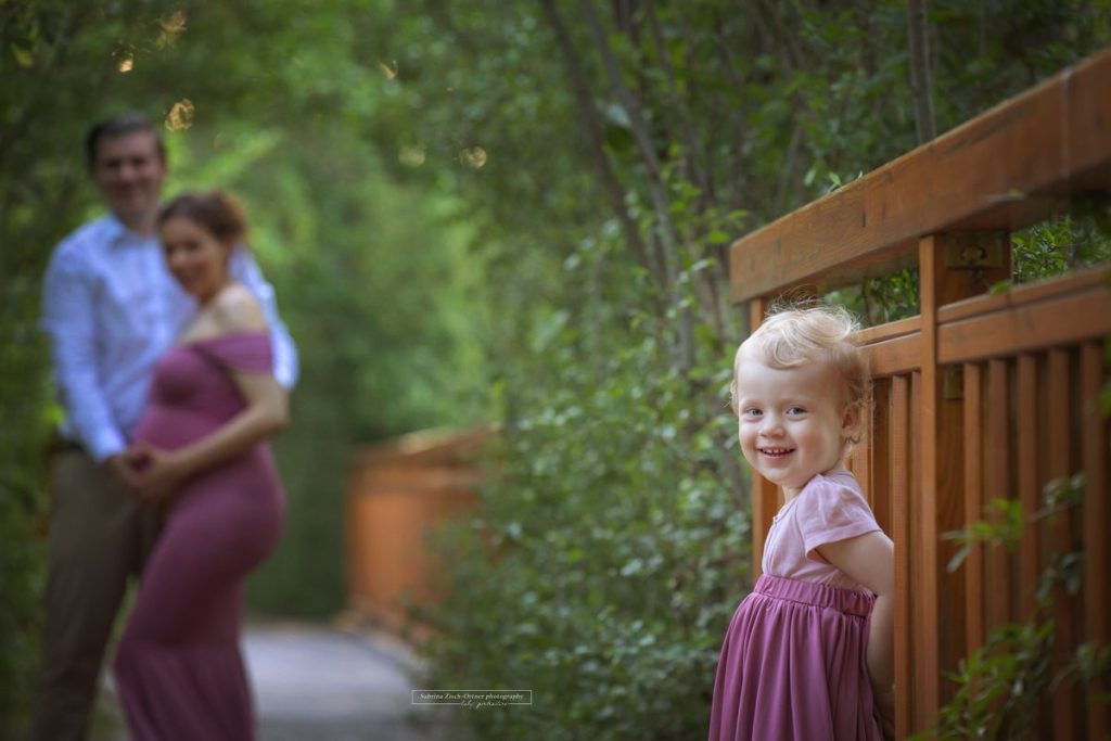 grinsende zwei jährige Mädchen beim Babybauch Outdoor Shooting