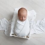 neugeborener Junge in weißen Bett mit weißen Tüchern beim Fotoshooting