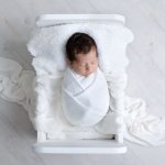 neugeborenes Maedchen liegt in weißen Bett für ihre Fotos