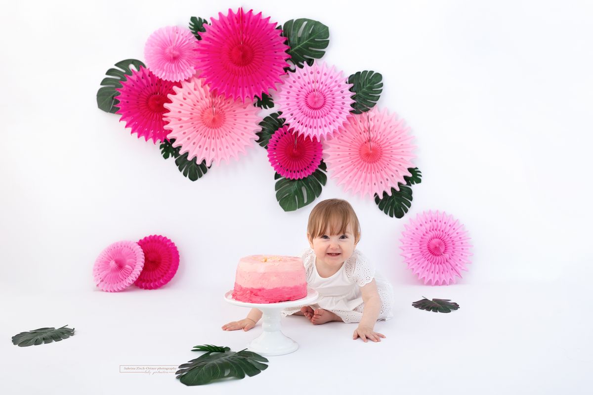 rosa Fächer und grüne Blätter mit rosa Torte in 3 Farben und ein grinsendes Geburtstagskind