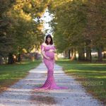 wunderhübsche Mama mit kugelrundem Babybauch und figurbetontem Rosa Schwangerschaftskleid