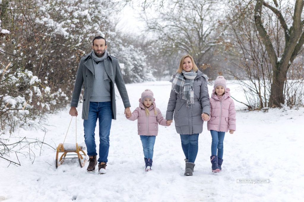 Eltern machen einen Spaziergang mit den Töchtern im verschneiten Februar