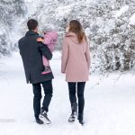 Familie Mama, Papa und Tochter gehen im Schnee spazieren