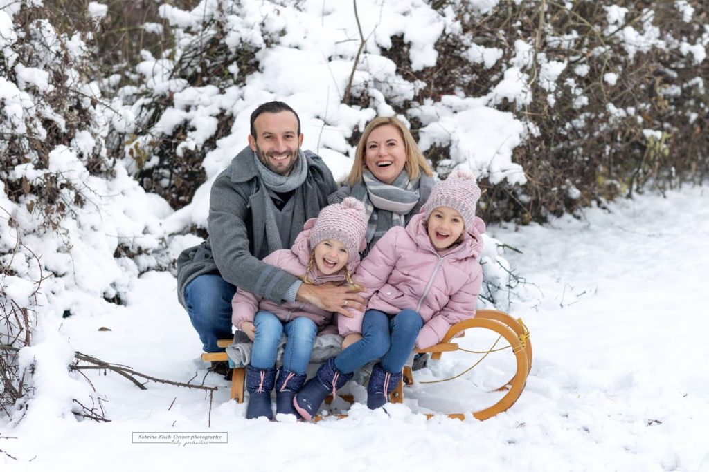 Familienfoto mit Rodel im Winter mit Schnee