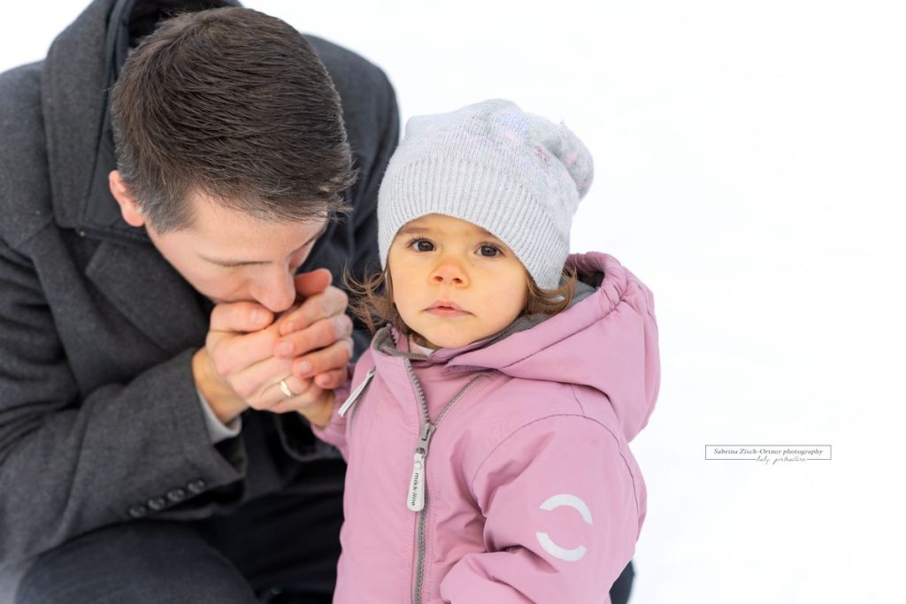 Papa waämt die Hand der Tochter beim Fotoshooting