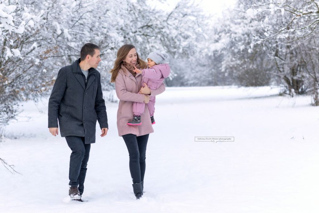 Spazieren im weißen Schnee mit Mama und Papa