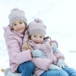 winterliche Geschwisterfoto mit rosa Jacken, Hauben und Handschuhen