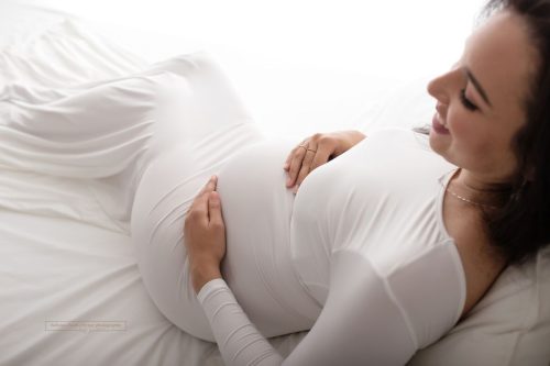 Lächelnde sitzende Schwangere bei ihrem Fotoshooting