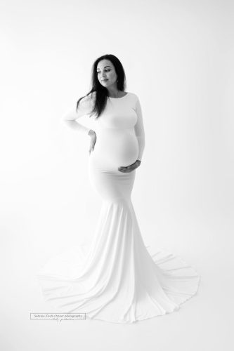 Schwangere in einem eleganten Schwangerschaftskleid bei ihrem gebuchten Fotoshooting