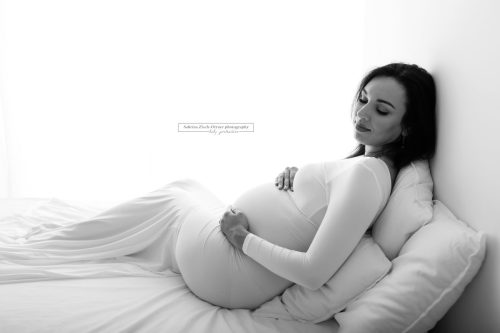 wunderschöne Schwangere bei ihrem Fotoshooting mit Bett