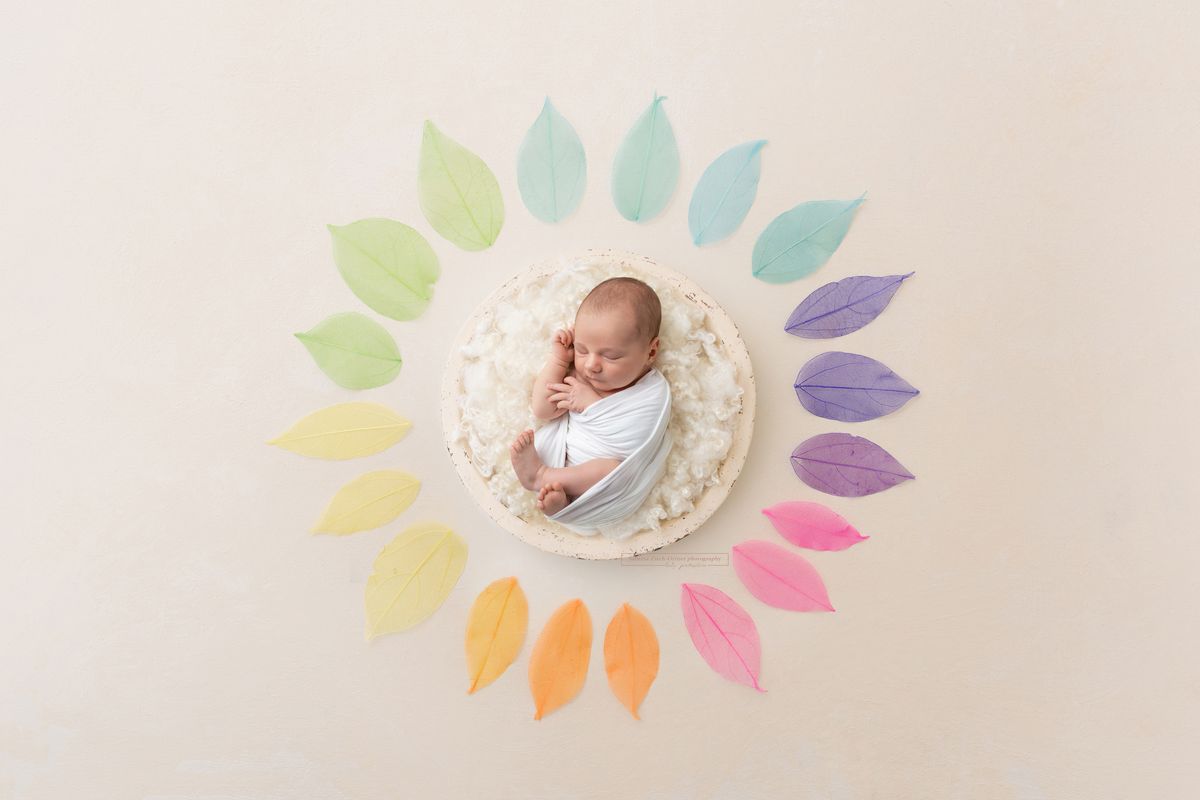 Baby in einem Nest aus regenbogenfarbenen Blättern