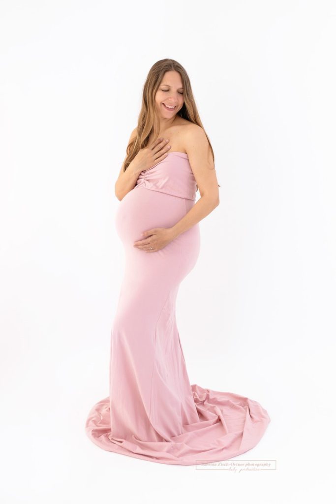 Bald Mama eines Mädchens hat rosa Babybauchkleid für ihr Fotoshooting an
