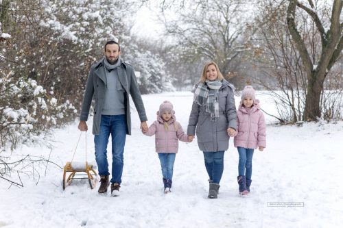 Eltern machen einen Spaziergang mit den Töchtern im verschneiten Februar