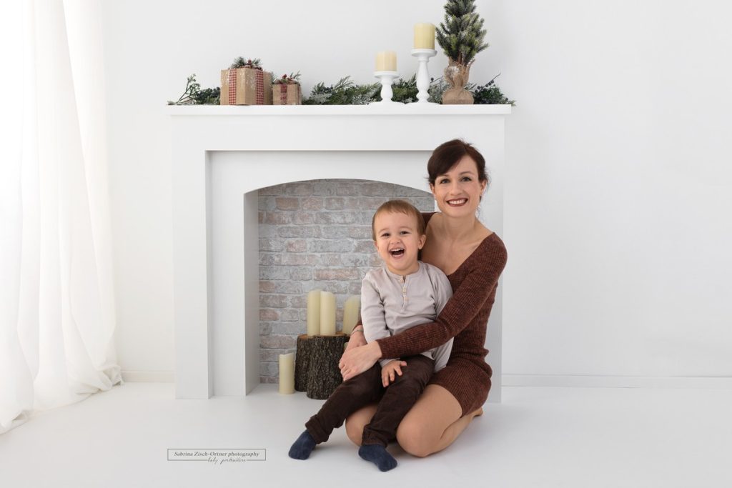 Mama und Sohn Foto vor weißen weihnachtlich geschmückten Kamin