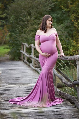 elegante bald Mama bei ihrem Outdoor Schwangerschaftsfotos auf Holzbrücke