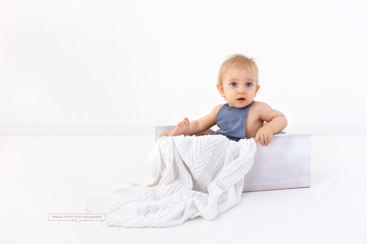 erstaunte Blick beim Babyfotoshooting während Bub in Bettchen sitzt