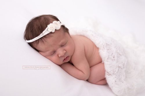 junges Baby mit weißer Decke und weißem Haarband