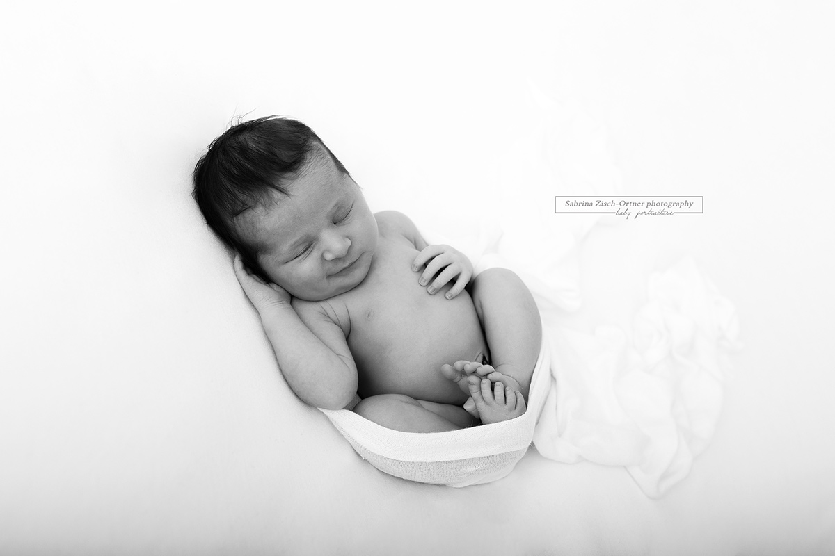lächelndes neugeborenes Baby in Schwarz Weiß