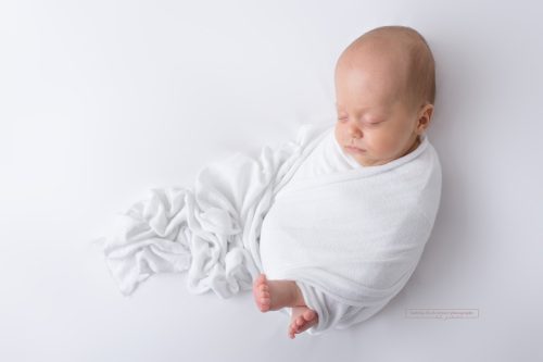 neugeborene Junge eingewickelt in weißes Tuch bei seinem Fotoshooting in Wien