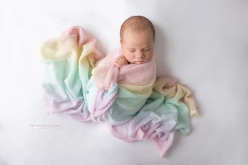 neugeborenes Baby eingewickelt in pastellfarbenes Regenbogentuch