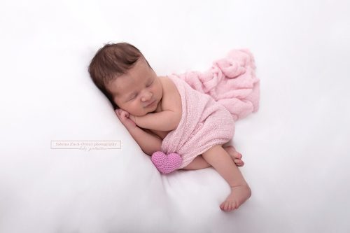 neugeborenes Baby mit rosa Tuch und rosa Herzchen
