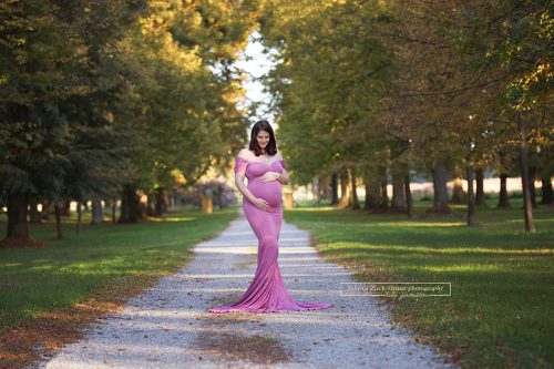 wunderhübsche Mama mit kugelrundem Babybauch und figurbetontem Rosa Schwangerschaftskleid