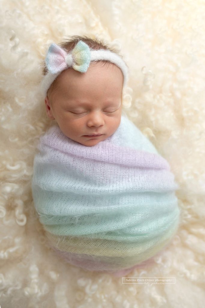 Baby eingepackt in Regenbogen Farbenes Tuch mit Haarband