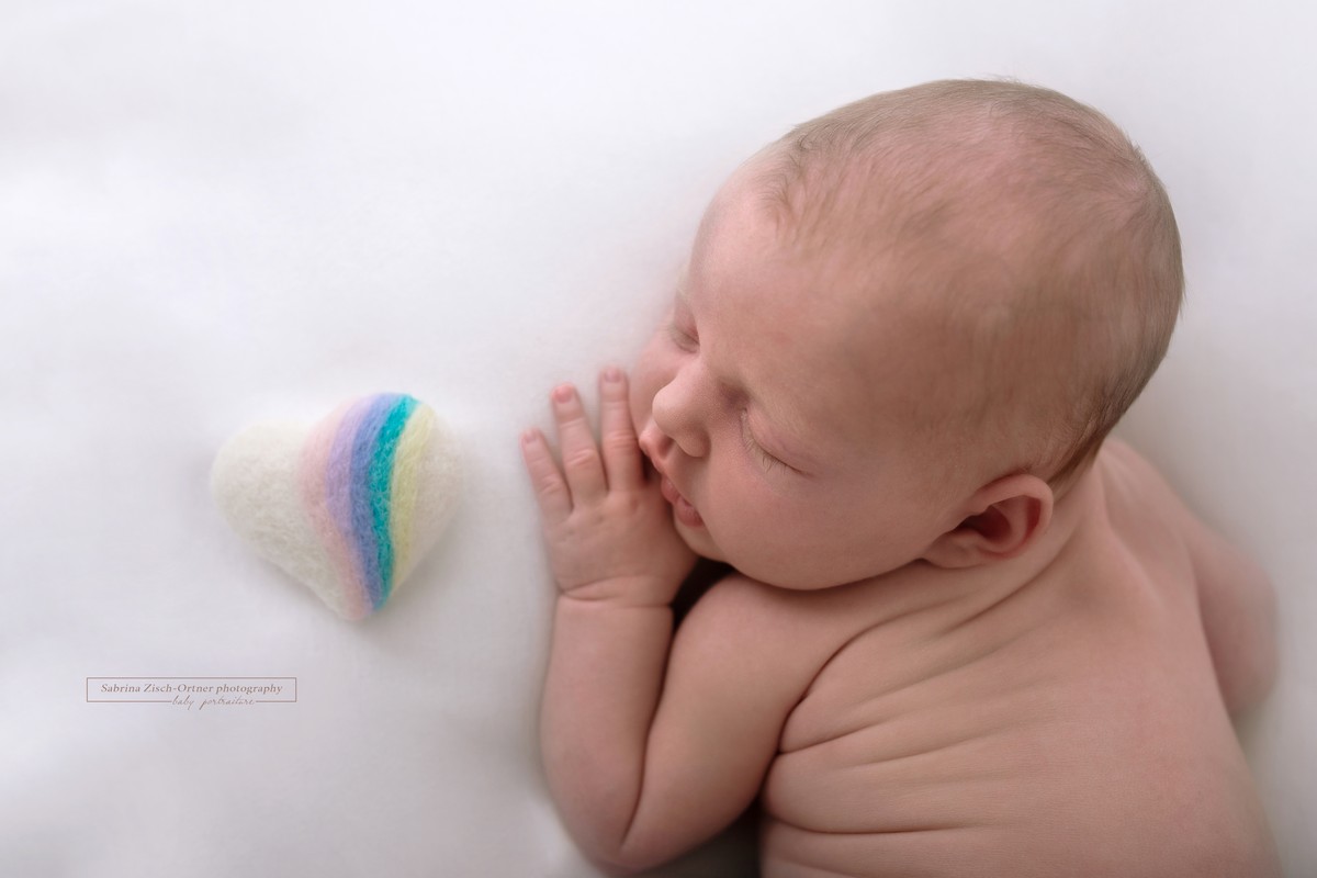 Filz Herz mit kleinem Regenbogen liegt neben Neugeborenen Baby
