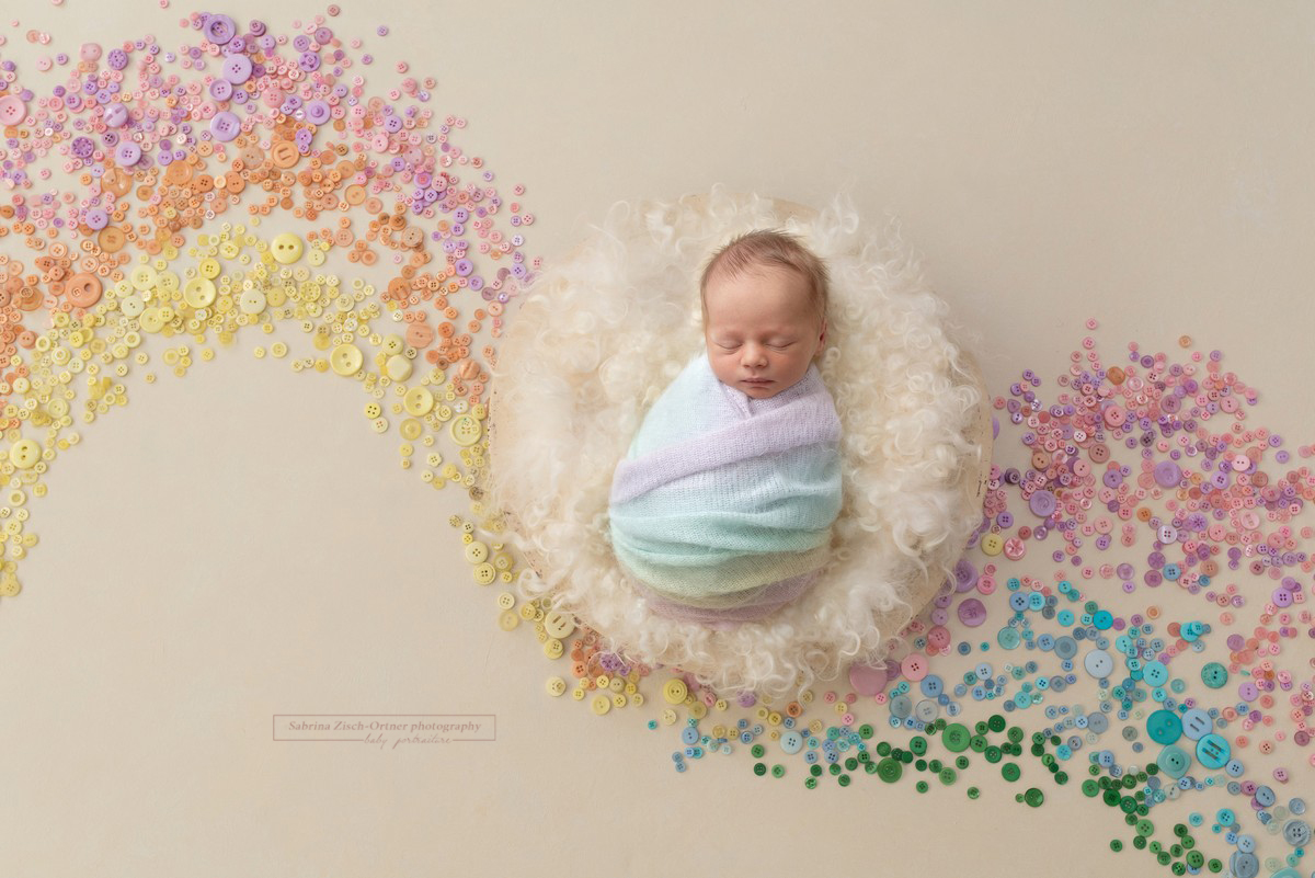 Foto mit einem Regenbogen aus Knöpfen und einem Baby