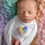 Neugeborenes Regenbogen Baby auf Decke mit Herzchen beim Shooting mit Sabrina Zisch Ortner