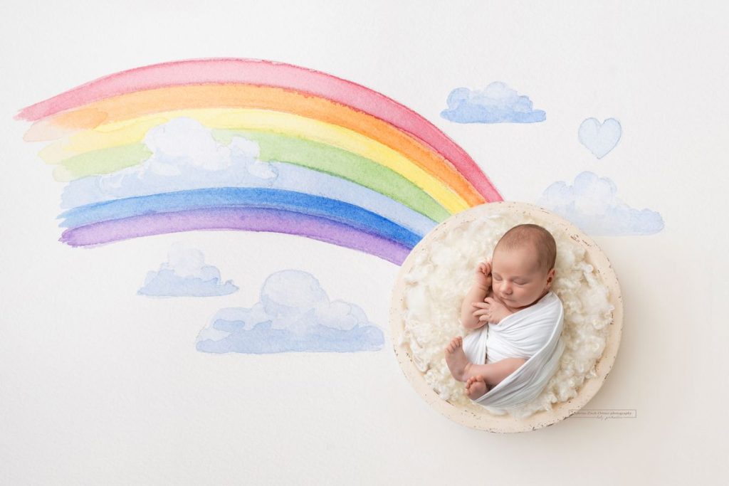 handgezeichneter Regenbogen mit Wolken und ein Baby