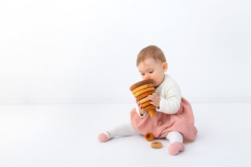 Baby Kind spielt mit Holzspielzeug beim Fotoshooting