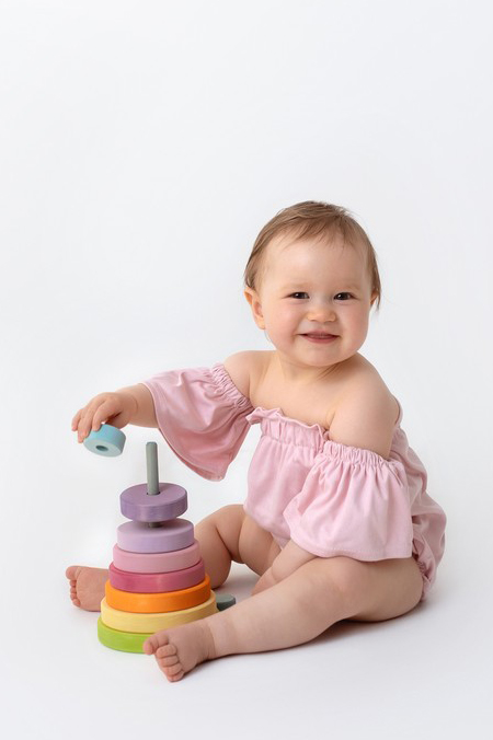 Holzspielzeug in Regenbogenfarben beim Baby Fotoshooting