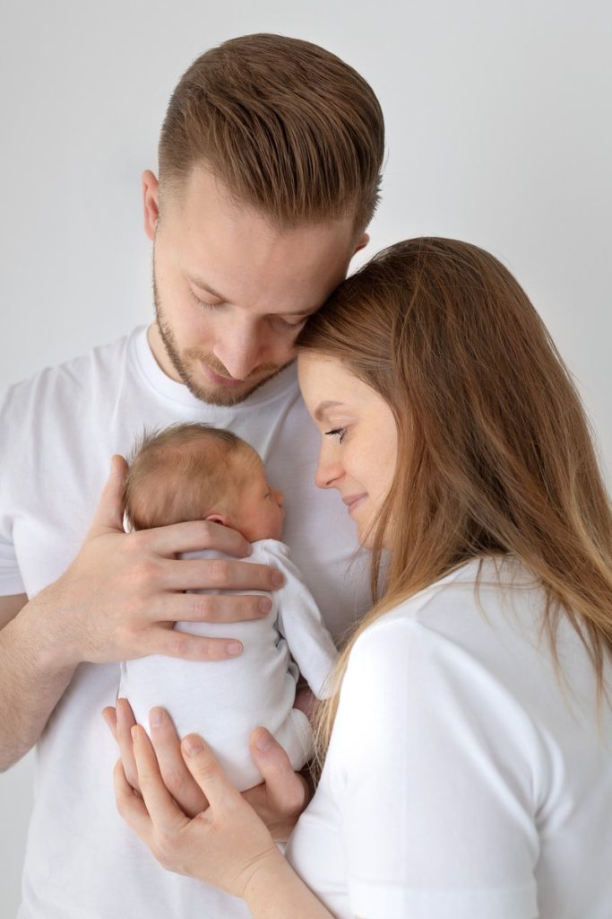 Neugeborenes Baby mit seinen Eltern beim Babyshooting
