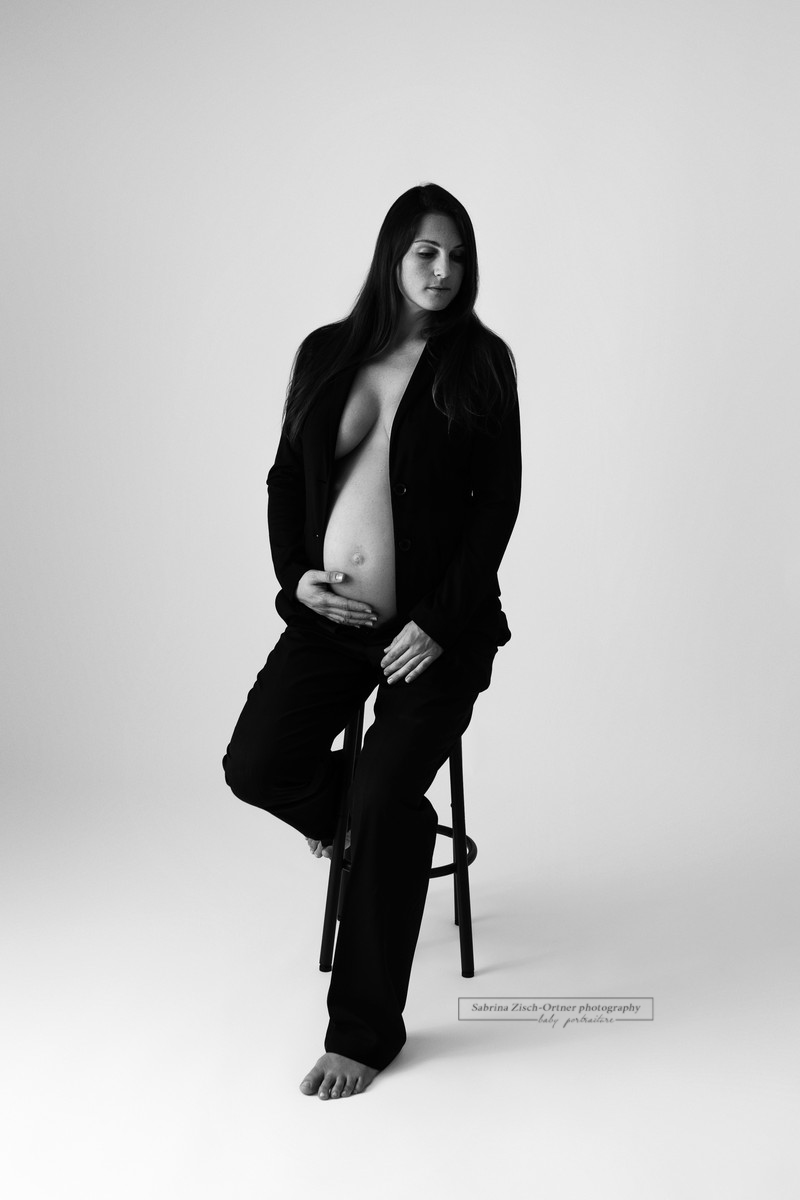 Schwangere im Hosenanzug beim Fotoshooting mit nackigem Bauch