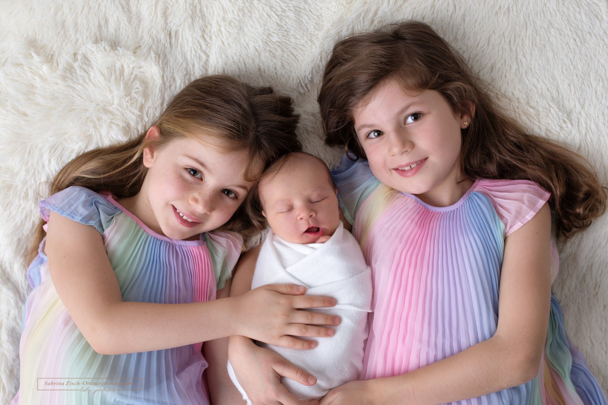 Schwestern in Regenbogenkleidern mit Baby